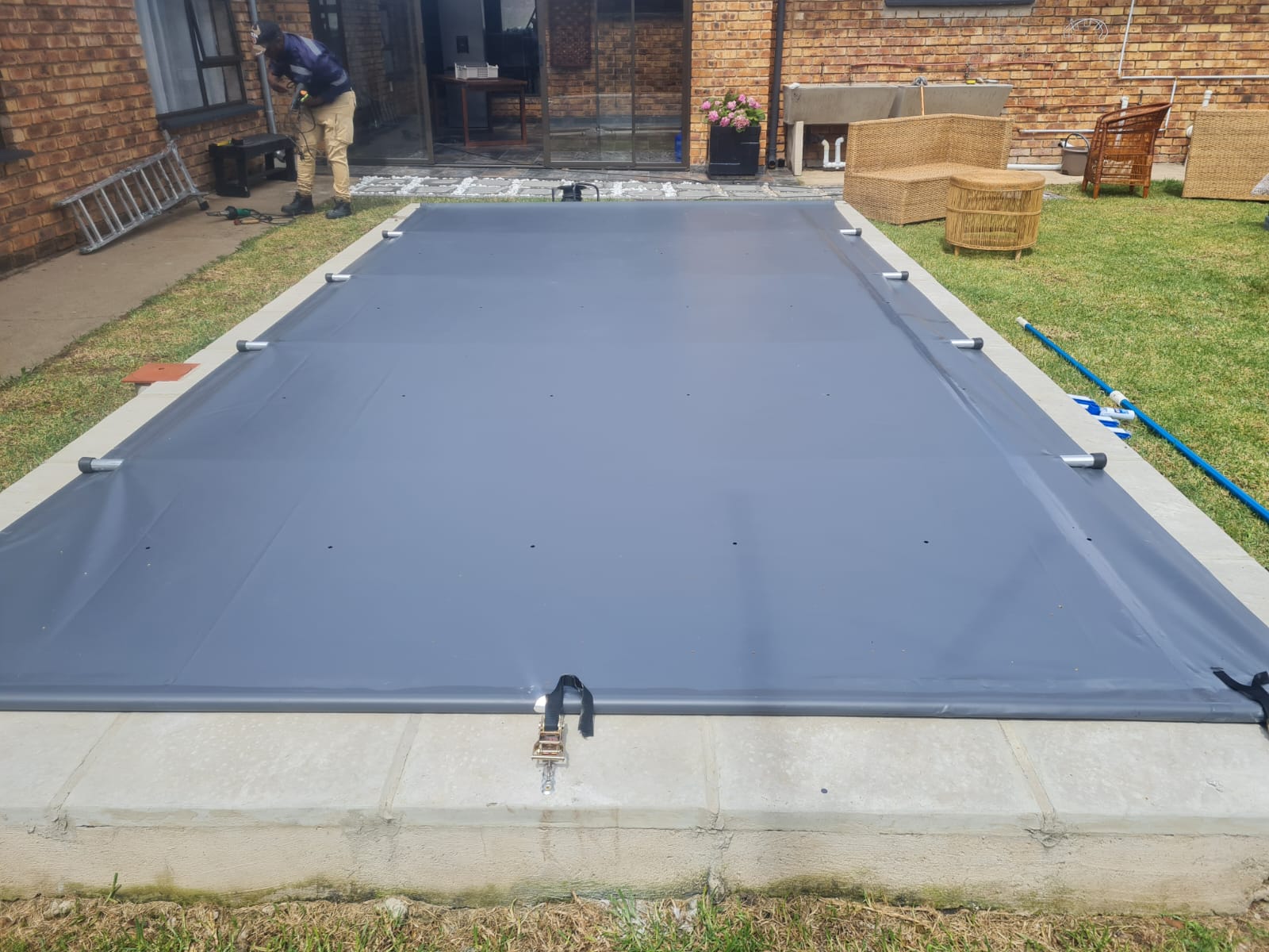 Team fitting a grey pool cover to a garden pool